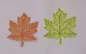 Preview: Stickdatei Set Herbstblätter inkl. ITH Anhänger, Foto mit 2 Blättern auf hellem Untergrund. Gestielte Blätter aus Organza, in orange oder grün, aufgestickte Blattaderstruktur selben Farbtons.