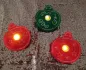 Preview: Stickdatei Set Christmas Lights (div. Rahmengrößen). Foto zeigt 3 LED-Cover in Form von Weihnachtsbaumkugeln, in jeder davon steckt mittig ein leuchtendes LED. Aus grünem, bzw. orangem Filz, filigran verziert.