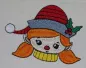 Mobile Preview: Stickdatei Set Christmas Faces Vollstick, Foto zeigt auf hellen Stoff gesticktes buntes Kopfmotiv eines Mädchens mit Mütze.