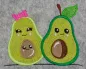 Preview: Stickdatei Set Sweet Avocados, Foto mit zwei grün gehaltene Avocados nebeneinander auf graumeliertem Filz. Die eine mit pinker Schleife und braunem Kern im Inneren, beide mit Pausbackengesicht. Die andere mit Stiel und grünem Blatt, einem Pausbackengesich