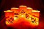 Preview: Stickdatei Set ITH Lichtbeutel Halloween (13x18 Rahmen) plus Einzelmotive, Foto mit 5 hell erleuchteten Ausfertigungen auf Felluntergrund. Beutel aus hellem Stoff mit Motiven (Fledermäuse; Kürbisse) und Schriftzügen.