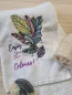 Preview: Stickdatei Set Enjoy the Colours! Farbenfrohe Herbstblätter mit Schriftzug in schöner Schreibschrift auf gefaltetem Handtuch. Im Ausschnitt teilweise Seifenstück und Luffaschwamm sichtbar.