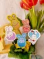 Preview: Stickdatei Set Osterhasen ITH Stabdesigns, Foto mit 5 Designstäben, in einem Blumentopf mit Blume steckend, Tulpenstrauß im Hintergrund. Motive: 4 mal Osterhase in halber Eierschale; 1 mal Osterhase, der ein Osterei stemmt.