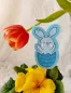 Preview: Stickdatei Set Osterhasen ITH Stabdesigns, Foto mit Designstab, in einem Blumentopf mit Blume steckend, Tulpe über dem Artikel hängend. Auf türkisem Filz gestickter Osterhase in halber Eierschale, der die Pfoten nach oben streckt.