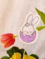 Preview: Stickdatei Set Osterhasen ITH Stabdesigns, Foto mit Designstab, der in Blumentopf mit Blume steckt, Tulpe neigt sich im Hintergrund herab. Osterhase auf hellem Filz gestickt und in halber rosa-lila Eierschale sitzend.