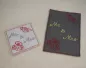 Preview: Stickdatei Set Hochzeit, Foto zeigt 2 Karten aus Filz. Eine dunkel, hochkant, Bestickung in rot und gelb: Rosenköpfe, Schriftzug "Mr. & Mrs.". Die andere quadratisch, hell, selbe Bestickung, aber in grau-rot.