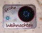 Preview: Freebie Stickdatei ITH Mug Rug Frohe Weihnachten (10x10 und 13x18), querformatiger Tassenteppich, silbrig-metallischer Untergrund. Schriftzug "Frohe Weihnachten" und Umrandung des Abstellplatzes in rot, blaue Stickereien Eiskristalle. Abstellplatz kreisru