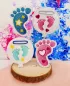 Preview: Stickdatei Set Stabdesigns zur Geburt, Foto mit 4 Dekostab-Designs, präsentiert auf Holzscheibe, welche auf orangem Fell liegt. 2 mal Luftballon mit Einstecköse, bestickt mit je einem Paar Füße pink bzw. türkis, umgeben von Herzen bzw. Sternen. 2 mal Fuß