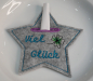 Preview: Stickdatei Set Happy new Year Tischdeko (div. Rahmengrößen) , Foto mit Tasche in Sternform auf hellem Teller, in der Einstecköffnung ein gerolltes Papier. Grauer Filz, bestickt mit Schriftzug "Viel Glück" und Glücksklee.