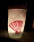Preview: Stickdatei Set ITH Lichtbeutel Unterwasserwelt, Foto mit hell erleuchtetem Lichtbeutel in dunklem Raum. Auf hellem Stoff orangerote Bestickung mit Muschel. 