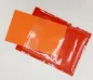 Preview: Stickdatei Set ITH Geburtstagskarten (10x10 u. 13x18), Foto mit einer Blankokarte in orangerot mit transparenter Folie, die an einer Seite nicht vernäht ist. Ein auf dem Bild teilweise eingeschobener Papierstreifen macht die transparente Folie, unter die