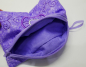 Preview: Stickdatei Set BLANKO ITH Taschen hochkant mit Reißverschluss, Foto mit Tasche auf Untergrund liegend, Reißverschluss komplett geöffnet und Seite leicht umgestülpt, so das das lila Innenfutter sichtbar ist. Tasche mit lila Reißverschluss ist rechteckig im