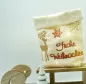 Preview: Stickdatei Set 6 winterliche Lichtbeutel (für den 13x18 Rahmen), Foto mit Lichtbeutel aus hellem Stoff mit umgeschlagenem Rand. Bestickung in gold und rot: Hirsch, Eiskristalle, Schriftzug "Frohe Weihnachten".