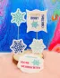 Preview: Stickdatei Set Weihnachts-Stabdesigns, Foto mit 5 Designs vor buntem Hintergrund auf Holzscheibe mit orangem Fell darunter. 3 mal unterschiedliche Eiskristalle (blau, grün bzw. türkis). 2 mal mit Einstecköffnung, Eiskristallbestickung, rahmenartiges, bzw.