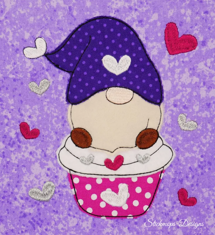 Stickdatei Set 5in1 Lovegnome Doodle-Applikationen, Foto mit Applikation auf lila-hell gemustertem Stoff. Gnom, umgeben von Herzchen, trägt gepunktete Mütze mit Herz und sitzt in Hut.