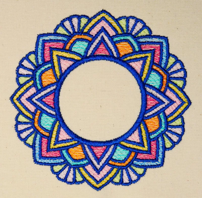 Stickdatei Set Mandalas + Split Mandala (div. Größen), Foto zeigt Ausfertigung des Ornaments auf hellem Stoff. Buntes Mandala-Ornament aus Bogen und Zacken mit kreisrundem, freiem Zentrum.