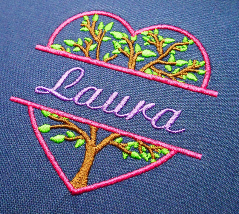 Preview: Stickdatei Set Monogramm Motiv Baum inkl. ITH Schild. Foto zeigt auf dunkelblauem Stoff pinken Herzumriss, quer in 2 Teile zerteilt, beide Hälften mit oberer bzw. unterer Hälfte eines Baums gefüllt. Auf dem mittigen Platz dazwischen Schriftzug 