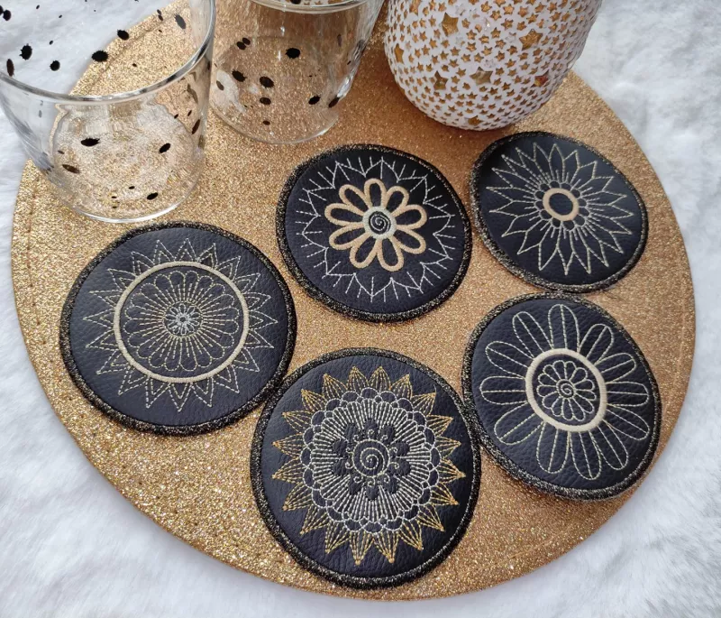 Stickdatei Set Mandala Coaster mit goldenem Garn auf schwarzes Kunstleder gestickt.