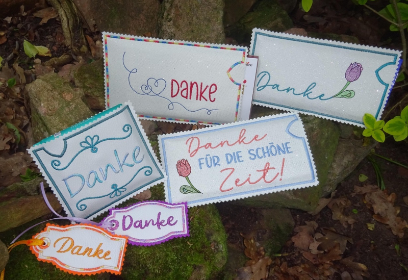 Stickdatei Set Danke mit ITH Schokohüllen, Anhängern, Grußkarten & Einzelmotiven, Foto zeigt 4 helle Hüllen, Bestickung mit Schriftzug "Danke"/"Danke für die schöne Zeit" mit Motiv/Ornament. Außerdem 2 helle Anhänger, Schriftzug "Danke".