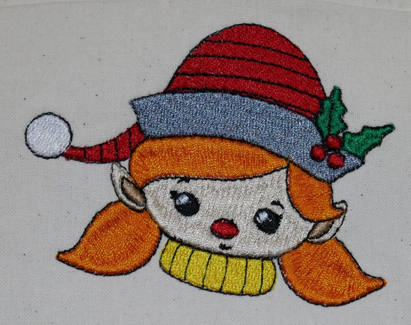 Stickdatei Set Christmas Faces Vollstick, Foto zeigt auf hellen Stoff gesticktes buntes Kopfmotiv eines Mädchens mit Mütze.
