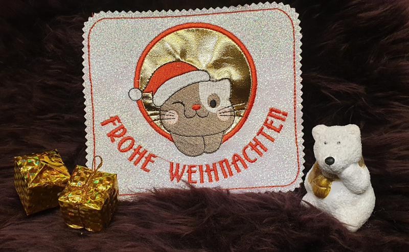 Untersetzer Tasse Katze mit Weihnachtsmütze und Schriftzug Frohe Weihnachten auf glitzerndem Stoff