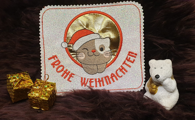 Preview: Untersetzer Tasse Katze mit Weihnachtsmütze und Schriftzug Frohe Weihnachten auf glitzerndem Stoff