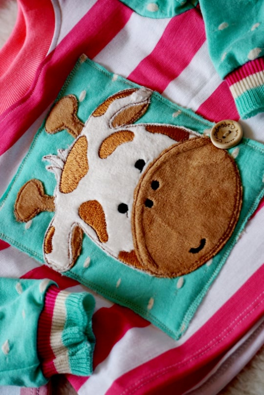 Stickdatei Giraffe Applikation + ITH Anhänger, Foto mit Giraffenkopfapplikation aus Plüschstoff auf rot-weiß-grünem Kinderpulli. Giraffenfarben crème und braun.