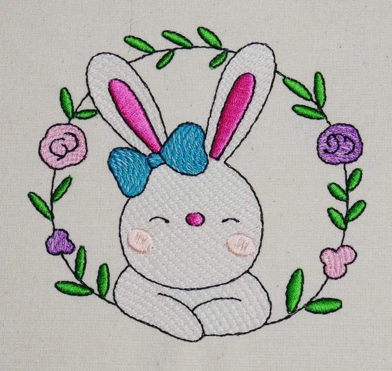 Osterhase mit floralem Kranz ausgestickt auf Baumwolle.