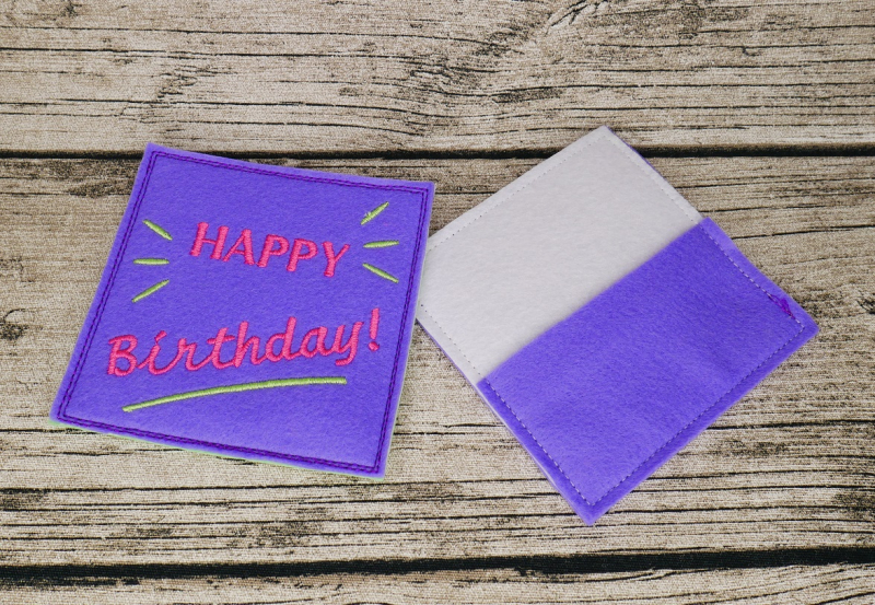 Stickdatei Set ITH Geburtstagskarten (10x10 u. 13x18), Foto mit 2 Abbildungen, wobei eine die Vorder- und eine die Rückseite einer Karte darstellt. Vorderseite lila mit Strahlen/Strich, Aufschrift "HAPPY Birthday". Rückseite hell mit lila Einstecktasche.