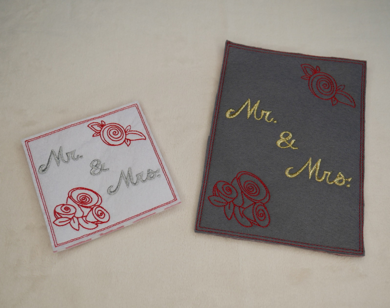 Stickdatei Set Hochzeit, Foto zeigt 2 Karten aus Filz. Eine dunkel, hochkant, Bestickung in rot und gelb: Rosenköpfe, Schriftzug "Mr. & Mrs.". Die andere quadratisch, hell, selbe Bestickung, aber in grau-rot.