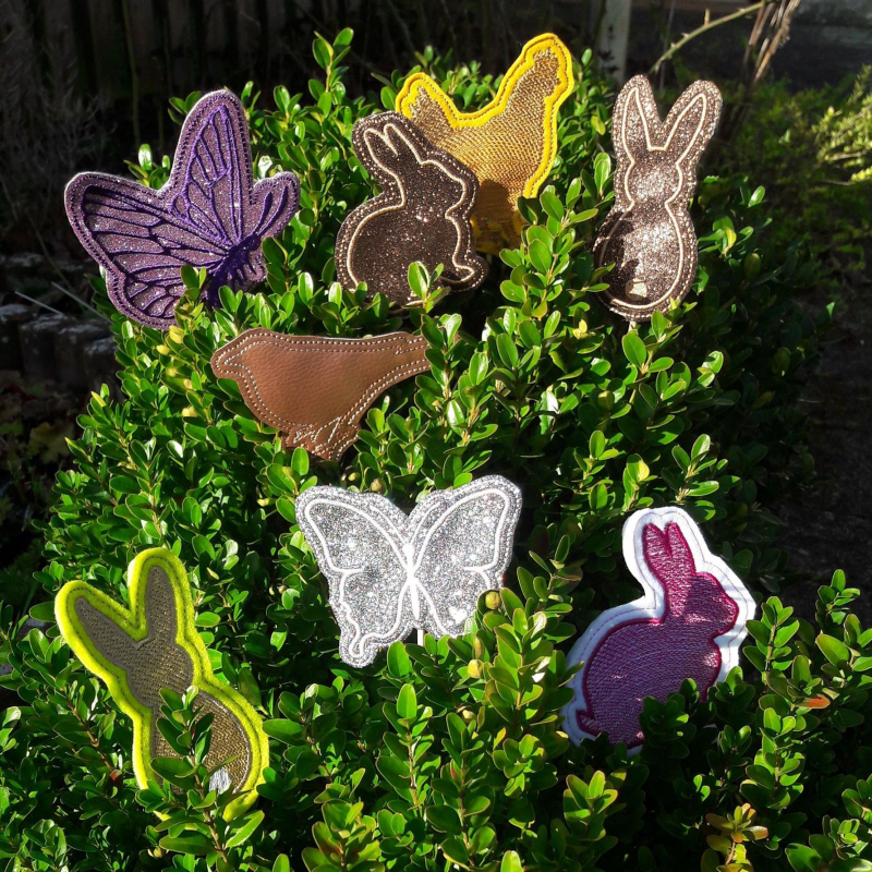 Stickdatei Set ITH Frühlings-Stabdesigns, Foto zeigt 8 Designstäbe in einem Blattgrünstrauß, diverse Farben. Motive: Schmetterling, Huhn, Hase, Vogel (diverse Ausführungen/Farben),