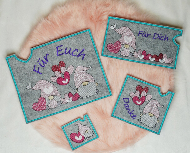 Preview: Stickdatei Set Lovegnomes ITH Geschenk- und Schokoladenhüllen, Foto mit 4 Ausfertigungen, zu sehen auf apricotfarbenem Fell. Alle Hüllen rechteckig, grauer Filz, Gnommotive in Variationen, dabei 3 mal mit Schriftzug 