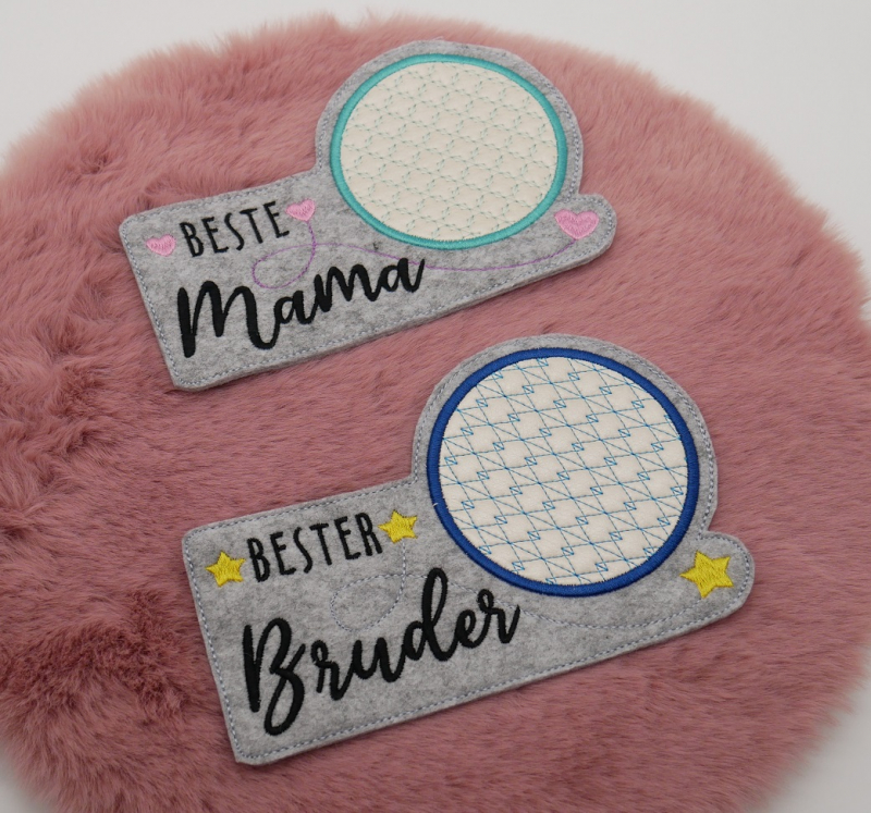 Stickdatei Set ITH Mug Rugs "die besten" inkl. Schriftzüge. Foto zeigt 2 schmale hellgraue Tassenteppiche mit darüber hinausgehendem kreisrundem Abstellplatz, dieser zart gemustert. Schriftzug "Beste Mama"/Schnörkel/rosa Herzchen, bzw. "Bester Bruder"/Sch