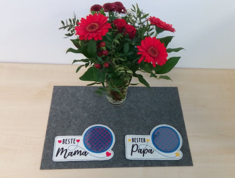 Stickdatei Set "die Besten" mit ITH Mug Rugs, Schokohüllen & Schriftzügen
Foto zeigt 2 schmale Tassenteppiche mit darüber hinausgehendem kreisrundem Abstellplatz, dieser dunkel und zweifarbig gemustert. Der eine Teppich weiß mit Schriftzug "Beste Mama"/
S