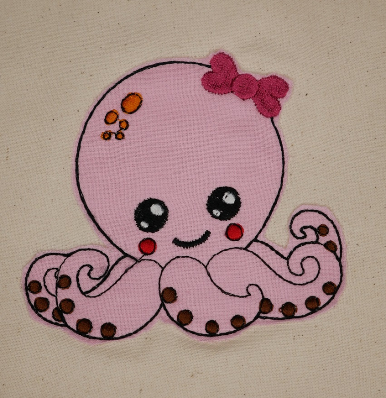 Stickdatei Octopus Applikation für Mädchen, Foto zeigt Oktopus in rosa auf hellem Stoff. Dicke rote Stickschleife am Kopf.