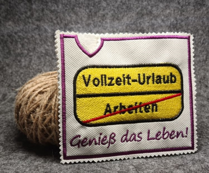 Stickdatei Set ITH Motivhüllen für viele Anlässe für Schokolade, Gutscheine u.a., Foto zeigt rechteckige helle Hülle. Bestickung mit Schildmotiv in Anlehnung an Ortsschild in gelb, schwarze Beschriftung darauf "Vollzeit-Urlaub", darunter durchgestrichenes