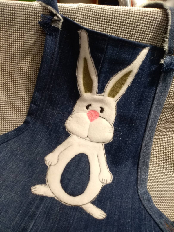 Preview: Stickdatei Set XXL Hase Charlie in 3 Variationen, Foto mit Ausfertigung auf dunkelblauer Schürze. Heller Fellhase mit Ostereibauch.