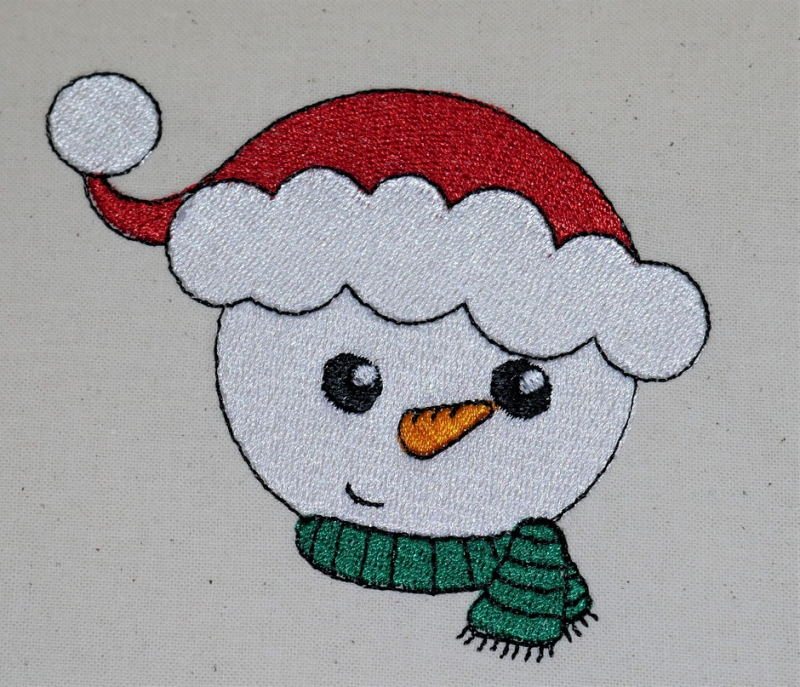 Stickdatei Set Christmas Faces Vollstick, Foto zeigt hellen Stoff, auf den ein Schneemannkopf mit Mütze und Schal gestickt ist (rot-grün-weiß-orange).