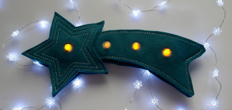 Stickdatei Set Christmas Lights (div. Rahmengrößen), Foto zeigt als LED-Cover Komet in dunkelblaugrün (Sternteil + Schweif), mit 4 Öffnungen, in die LED-Lichter eingesteckt sind.