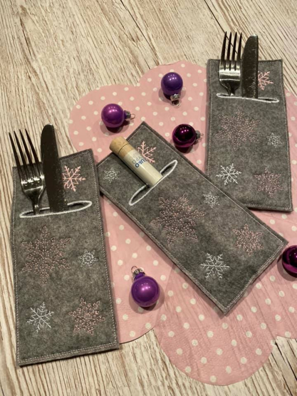 Stickdatei Set weihnachtliche ITH Bestecktaschen, Foto zeigt 3 längliche identische Taschen. Davon 2 besteckgefüllt, eine befüllt mit länglichem Behältnis für Schriftrolle/Gutschein. Dunkle grau-braune Taschen mit Eiskristallbestickung.