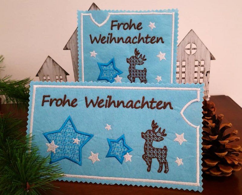 Stickdatei Set ITH Motivhüllen für viele Anlässe für Schokolade, Gutscheine u.a.. Foto zeigt zwei hellblaue Filzhüllen mit Sternen in blau und rosa, braun gemustertem Rentier, Schriftzug "Frohe Weihnachten". 1 mal quadratisch, 1 mal Querformat.