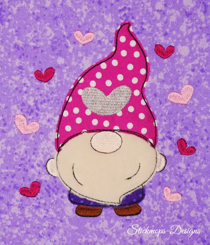 Stickdatei Set 5in1 Lovegnome Doodle-Applikationen, Foto mit Applikation auf lila-hell gemustertem Stoff. Von Herzchen umgebener Gnom, rot-weiß gepunktete Mütze mit Herz.