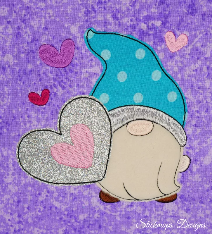 Stickdatei Set 5in1 Lovegnome Doodle-Applikationen, Foto mit Applikation auf Stoff, der lila-hell gemustert ist. Von Herzchen umgebener Gnom mit türkis-weiß gepunkteter Mütze und Herz haltend.