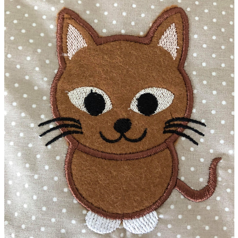Stickdatei Katze Applikation in 3 Größen, Foto zeigt Applikation auf braun-weiß getupftem Stoff. Brauner Filz, beige-weiß-schwarz-braune Bestickung. Stickdatei Katze Applikation in 3 Größen, Foto zeigt Applikation auf braun-weiß getupftem Stoff. Brauner Filz, beige-weiß-schwarz-braune Bestickung.