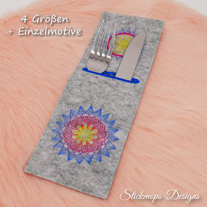 Stickdatei Set Mandala-Bestecktaschen + Einzelmotive, Foto mit auf orangefarbenem Fell liegender Hochkant-Tasche, befüllt mit Messer und Gabel, Schrifthinweis: 4 Größen + Einzelmotive. Einstecköffnung im eher oberen Teil, blau umrandet.