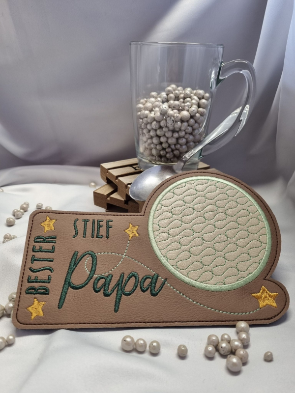 Stickdatei Set "die Besten" mit ITH Mug Rugs, Schokohüllen & Schriftzügen. Foto zeigt schmalen Tassenteppich aus braunem Kunstleder mit darüber hinausgehendem kreisrundem Abstellplatz, dieser beige-grün gemustert. Schriftzug "Bester Stiefpapa", gelbe Ster Stickdatei Set "die Besten" mit ITH Mug Rugs, Schokohüllen & Schriftzügen. Foto zeigt schmalen Tassenteppich aus braunem Kunstleder mit darüber hinausgehendem kreisrundem Abstellplatz, dieser beige-grün gemustert. Schriftzug "Bester Stiefpapa", gelbe Ster