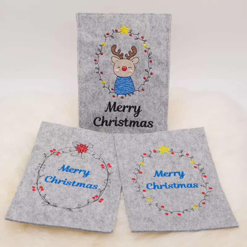 Stickdatei Set ITH Christmas-Cards - Grußkartenhüllen, Foto zeigt 3 Hochkant-Karten aus hellgrauem Filz. Bunte Bestickung mit jeweils diversem Kranz, darin Motiv Elch, bzw. Schriftzug "Merry Christmas".