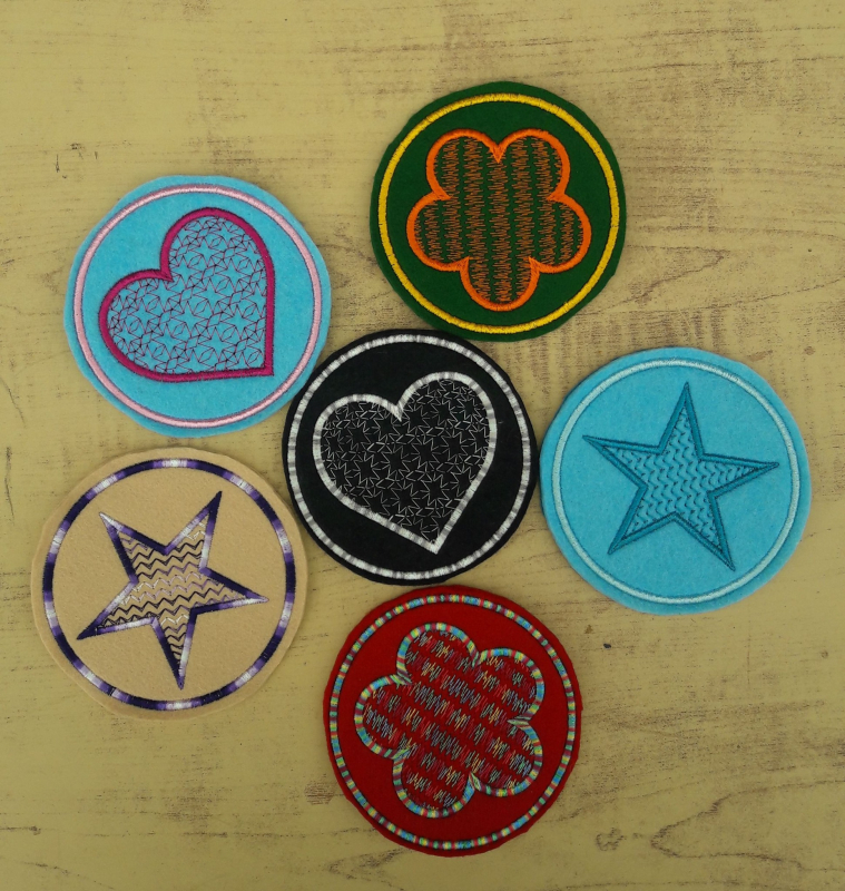 Stickdatei Set ITH Mug Rugs und Anhänger, Foto zeigt 6 kreisrunde Mug Rugs unterschiedlicher Grundfarben (türkis, grün, schwarz, ocker, rot). Darin in diversen Farben Symbol (Herz, Blüte, Stern), jeweils mit teilweise mehrfarbig filigran bestickter Innenf Stickdatei Set ITH Mug Rugs und Anhänger, Foto zeigt 6 kreisrunde Mug Rugs unterschiedlicher Grundfarben (türkis, grün, schwarz, ocker, rot). Darin in diversen Farben Symbol (Herz, Blüte, Stern), jeweils mit teilweise mehrfarbig filigran bestickter Innenf