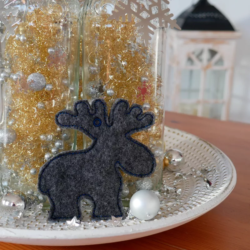 Stickdatei Set ITH Elchi (für 10 x 10 und 16 x 16 cm Rahmen), Foto zeigt 1 ausgestickten Elch aus antrazithfarbenem Filz in Elchumriss als Teil einer Weihnachtsdekoration. 