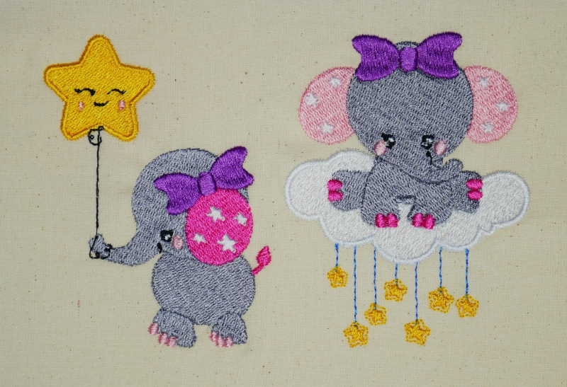 Stickdatei Set Elefanten (Vollstick) - ideal für Geschenke zur Geburt, Foto mit Stickerei auf hellem Stoff. Dargestellt ein Elefant auf Sternchen-Wolke und ein Elefant, dessen Rüssel einen Sternluftballon mit Gesicht hält.